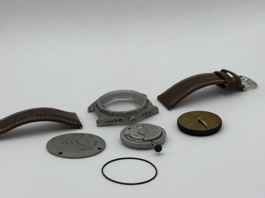 Elementy zegarka Ludowego przed montażem koperta mechanizm tarcza dekiel uszczelka i pasek