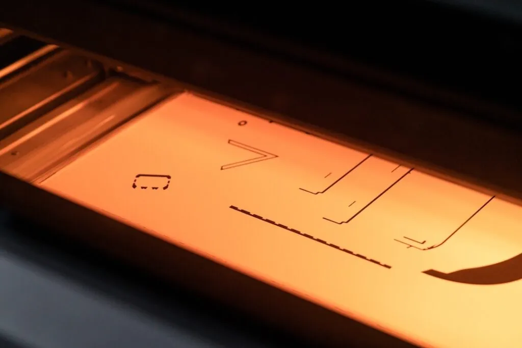 Proces druku 3D z plastiku metodą MJF w toku, widoczne przekroje części drukowanych na warstwie proszku polimerowego w komorze roboczej Spes3D.