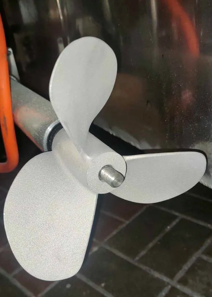 Matowa, trzyłopatowa śruba napędowa zamontowana na wale napędowym. Fizyczny prototyp elementu inżynieryjnego wykonany w technologii produkcji addytywnej (druk 3D) dla pojazdu typu amfibia, prezentujący precyzję wykonania łopat.